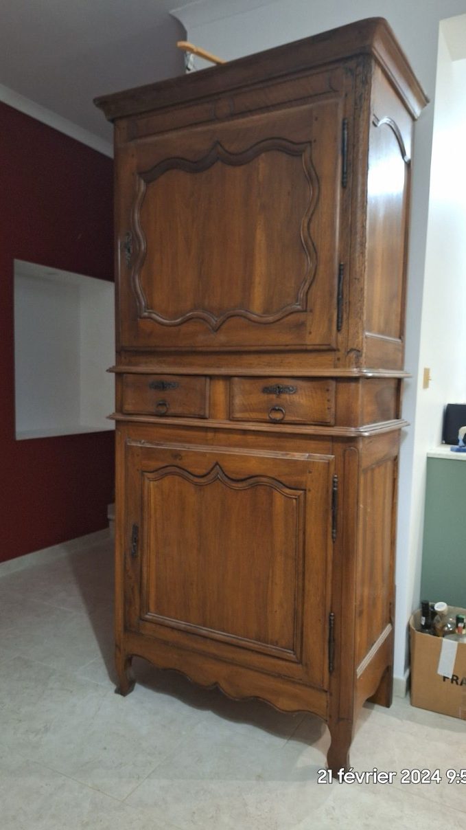 Ancien meuble en bois rénové, avec deux tiroirs et deux portes, situé dans un intérieur moderne aux murs clairs.