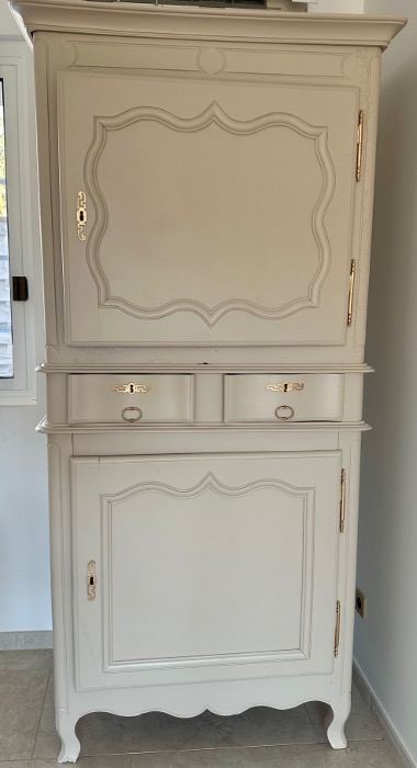 Ancien buffet rénové avec une teinte beige douce et des serrures dorées, alliant charme vintage et modernité.