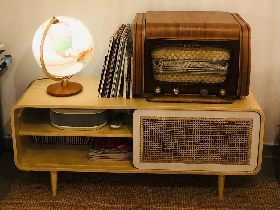 Un meuble vintage en bois clair avec un tourne-disque rétro, des disques de musique et un globe terrestre sur le dessus.